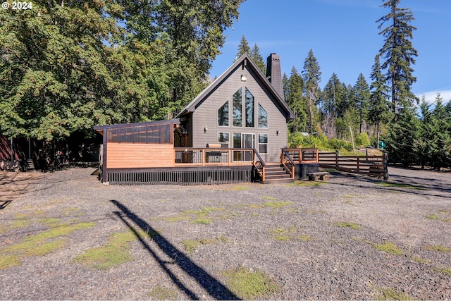 rear view of house featuring a chimney and a wooden deck