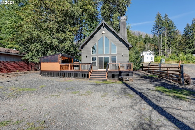 rear view of property featuring a chimney, fence, and a deck