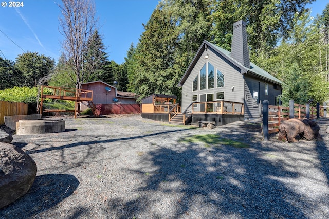 rear view of property with a chimney, fence, and a deck