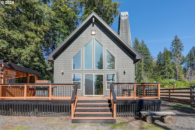 rear view of property with a chimney, a wooden deck, and fence