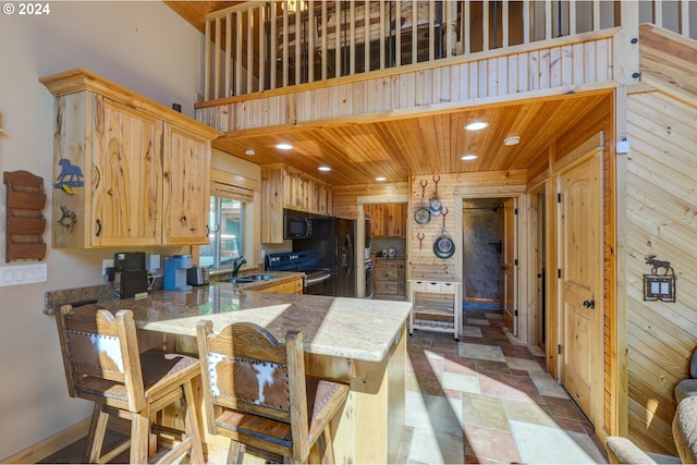 kitchen with a high ceiling, wood ceiling, a sink, a peninsula, and black appliances