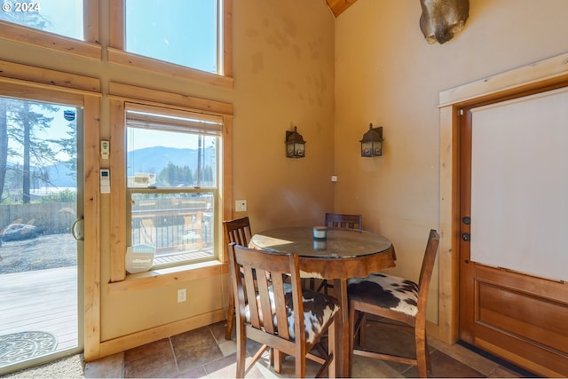 dining area with a towering ceiling, a mountain view, and baseboards