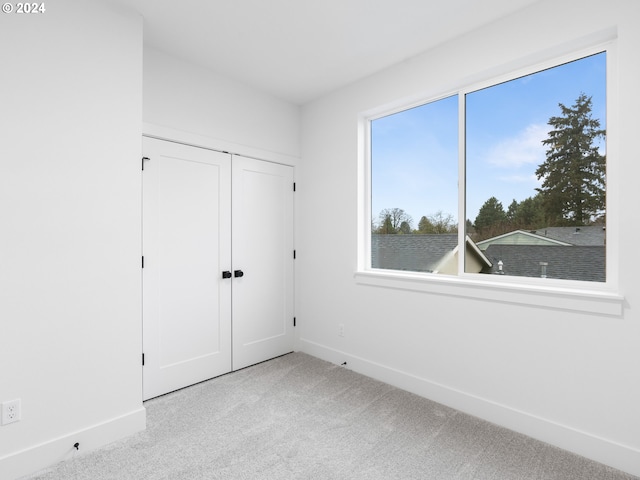 unfurnished bedroom featuring a closet and light colored carpet