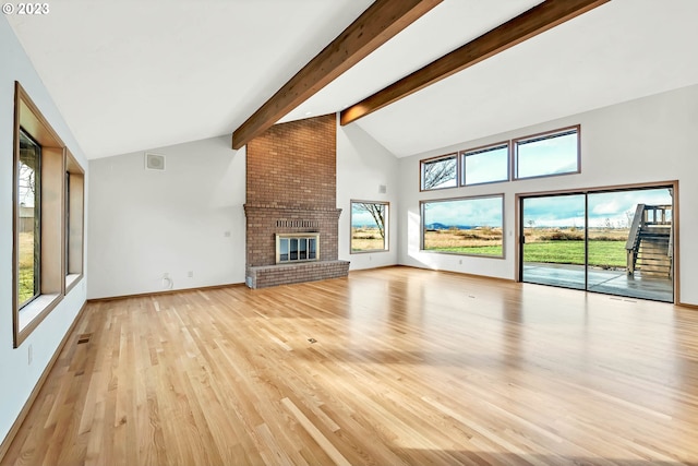 27717 Royal Ave, Eugene, OR 97402 - unfurnished living room featuring light wood-style flooring, beam ceiling, a fireplace, high vaulted ceiling, and baseboards