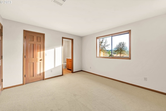 unfurnished bedroom featuring light carpet and ensuite bath