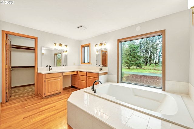 bathroom featuring vanity, tiled tub, and hardwood / wood-style floors