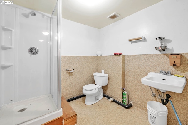 bathroom featuring toilet, walk in shower, sink, and tile walls