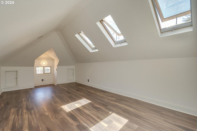 additional living space featuring dark hardwood / wood-style flooring and lofted ceiling with skylight