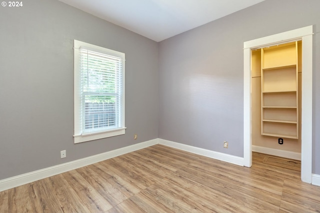 unfurnished bedroom with light hardwood / wood-style floors, a spacious closet, and a closet