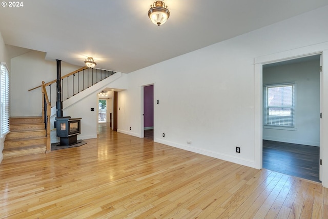 unfurnished living room featuring a wood stove and light hardwood / wood-style flooring