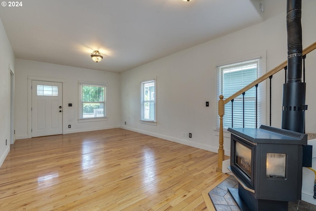 foyer entrance featuring a wood stove and light hardwood / wood-style flooring