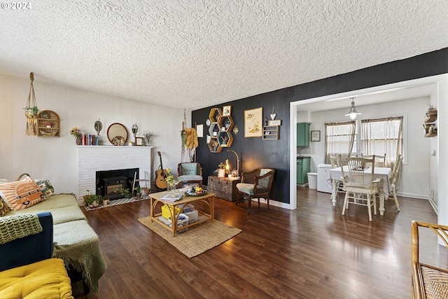 living room featuring hardwood / wood-style floors, a textured ceiling, and a brick fireplace