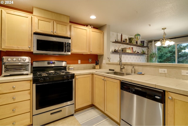 kitchen with a notable chandelier, light brown cabinets, sink, tile counters, and stainless steel appliances