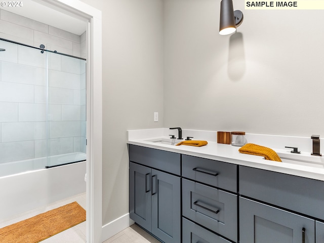 full bath with a sink, double vanity, and bath / shower combo with glass door