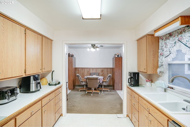 kitchen featuring ceiling fan, dishwasher, sink, wood walls, and light brown cabinetry