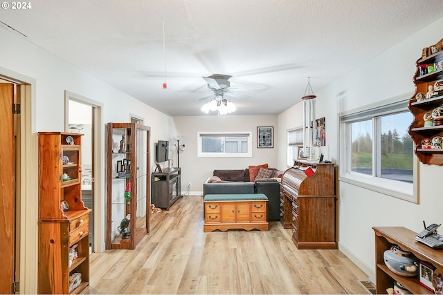 sitting room featuring ceiling fan, light hardwood / wood-style floors, and a textured ceiling