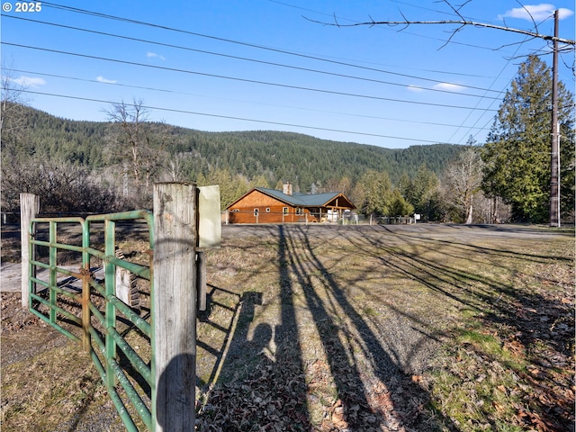 exterior space featuring a mountain view, fence, a gate, and a view of trees