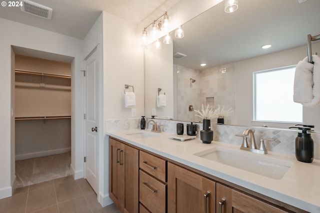 bathroom with tile patterned flooring, vanity, backsplash, and tiled shower