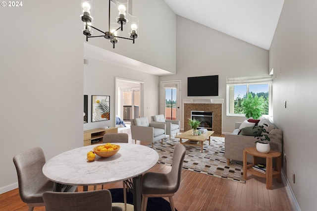 dining space with wood-type flooring, a notable chandelier, and high vaulted ceiling