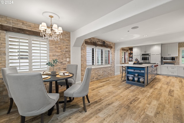 dining room featuring a chandelier, brick wall, and light wood-style floors