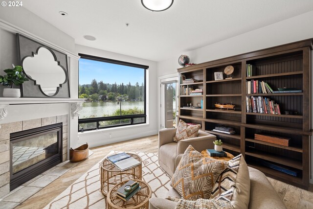 living area with a water view, a fireplace, and light hardwood / wood-style flooring