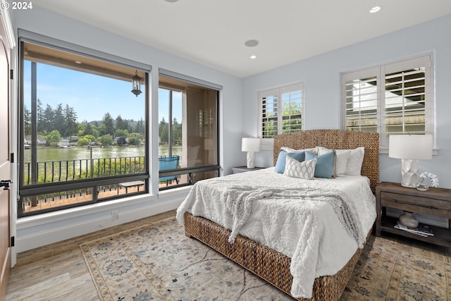 bedroom featuring hardwood / wood-style floors and a water view