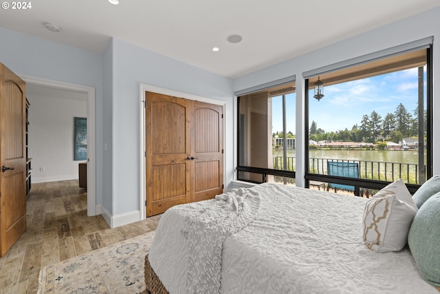 bedroom featuring wood-type flooring and a water view