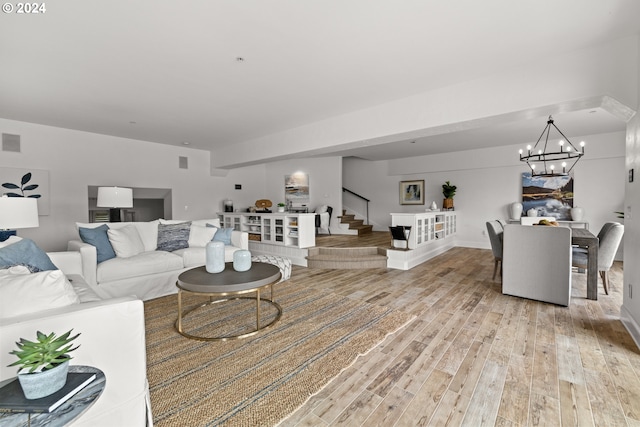 living area featuring light wood finished floors, visible vents, stairway, and an inviting chandelier