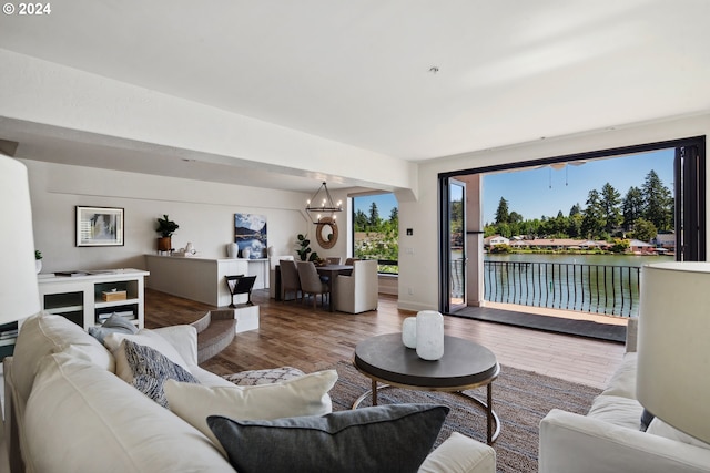 living room with an inviting chandelier, hardwood / wood-style floors, and a water view