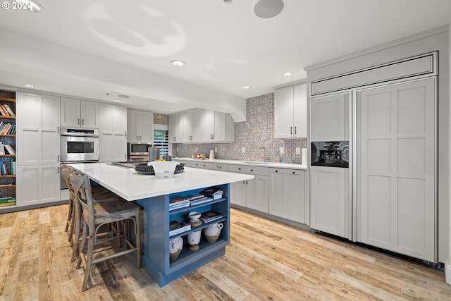 kitchen with appliances with stainless steel finishes, a center island, a kitchen breakfast bar, and light wood finished floors