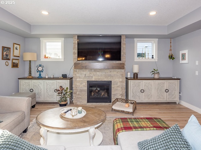 living room featuring a fireplace, light hardwood / wood-style flooring, and a textured ceiling