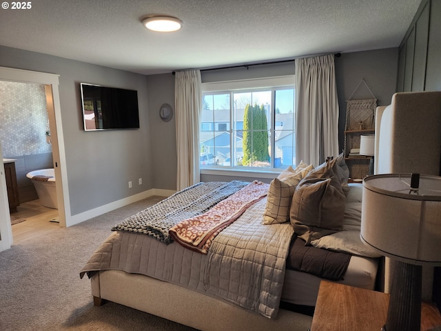 carpeted bedroom featuring ensuite bath and a textured ceiling