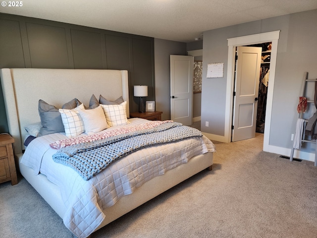 bedroom with a walk in closet, light colored carpet, and a closet