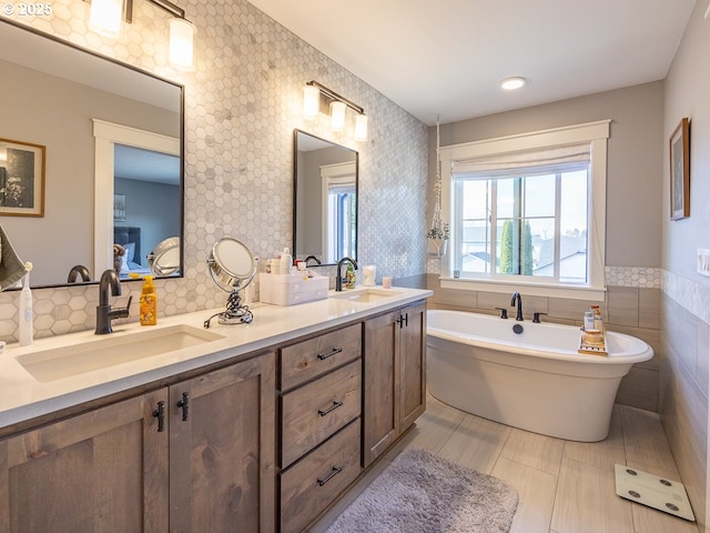 bathroom featuring tile walls, vanity, a washtub, and tile patterned floors