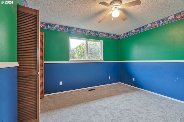 empty room featuring ceiling fan, carpet floors, and a textured ceiling