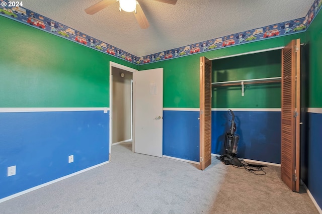 unfurnished bedroom with carpet flooring, ceiling fan, a closet, and a textured ceiling