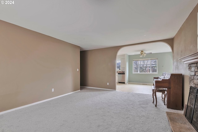 empty room featuring light carpet, a fireplace, and ceiling fan