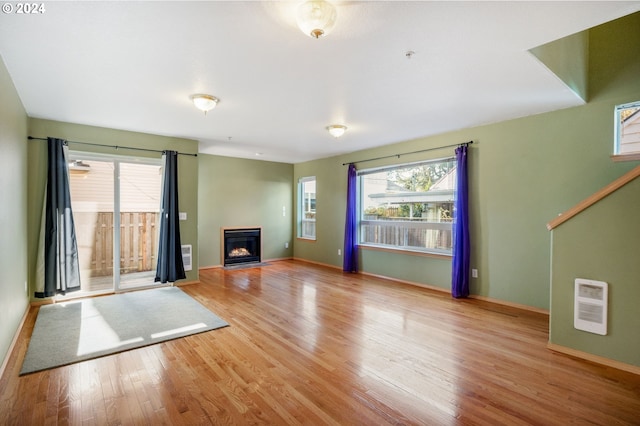 unfurnished living room featuring heating unit and light wood-type flooring