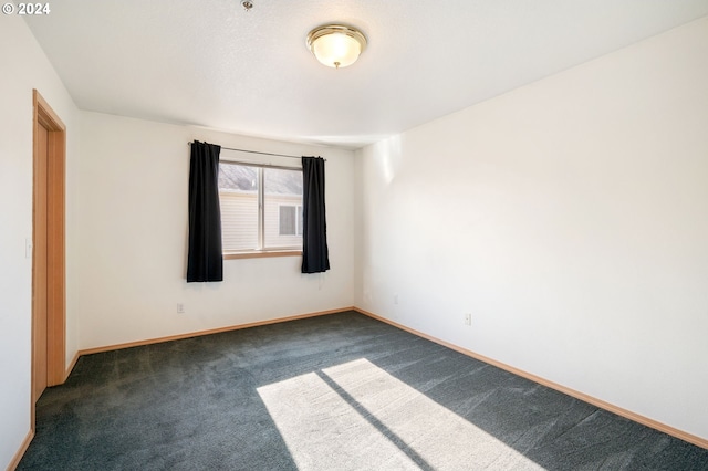 unfurnished room featuring dark colored carpet