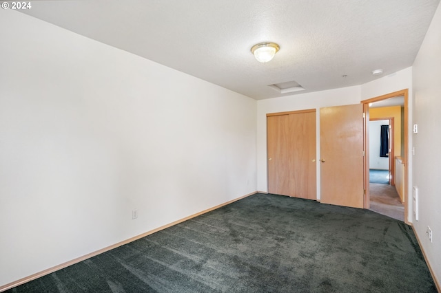 unfurnished bedroom with a textured ceiling and dark carpet