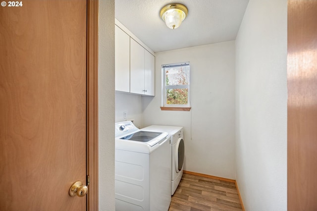 washroom featuring a textured ceiling, washing machine and dryer, light hardwood / wood-style floors, and cabinets