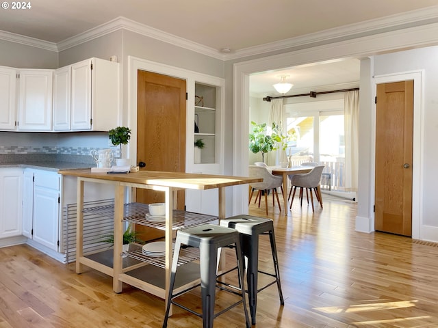 1035 NE Killingsworth St, Portland, OR 97211 - kitchen featuring light wood-style floors, white cabinets, ornamental molding, tasteful backsplash, and built in shelves