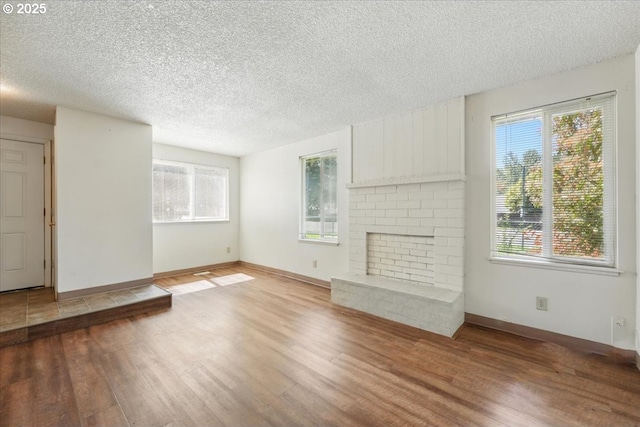 18495 SW Springfield St, Beaverton, OR 97078 - unfurnished living room featuring wood finished floors, a textured ceiling, a brick fireplace, and baseboards