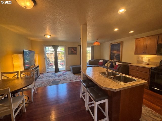 834 NW 3rd Ave, Canby, OR 97013 - kitchen with tile countertops, black appliances, open floor plan, a sink, and dark wood-style floors