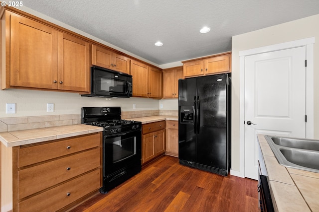 834 NW 3rd Ave, Canby, OR 97013 - kitchen featuring black appliances, tile counters, dark wood-style flooring, brown cabinetry, and recessed lighting