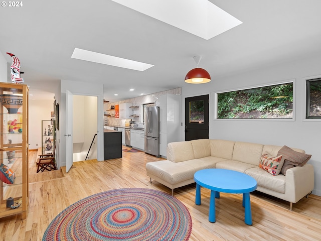 living room featuring light hardwood / wood-style flooring and a skylight