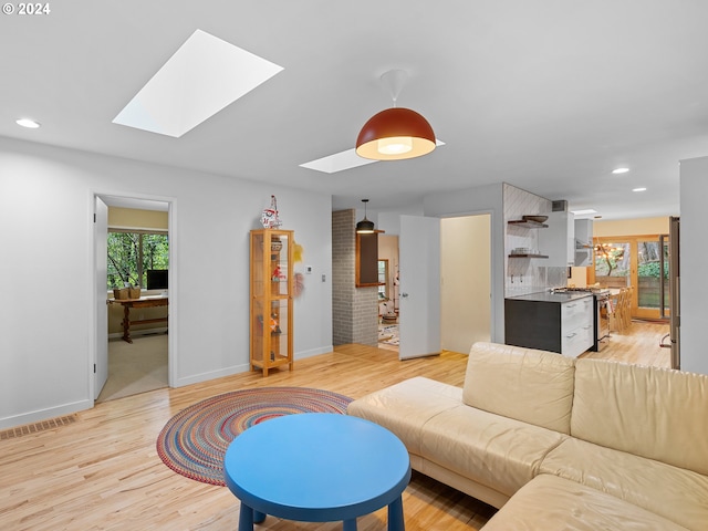 living room with a skylight, light wood-type flooring, and a wealth of natural light