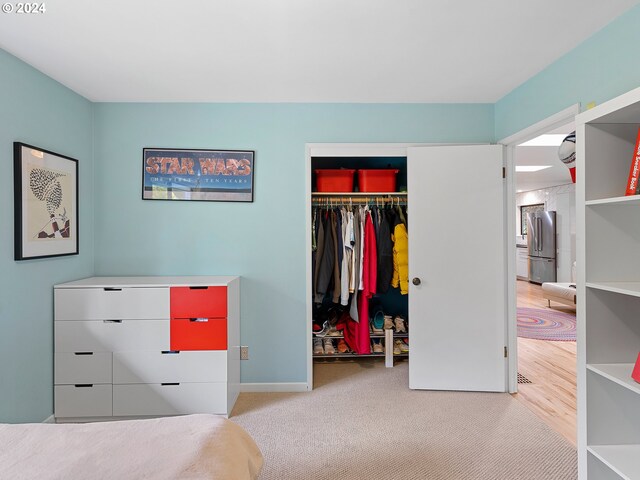 bedroom featuring stainless steel refrigerator, a closet, and carpet