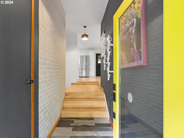 hallway with wood-type flooring and brick wall