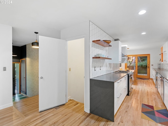 kitchen with light hardwood / wood-style floors, a notable chandelier, white cabinets, stainless steel gas range, and decorative light fixtures